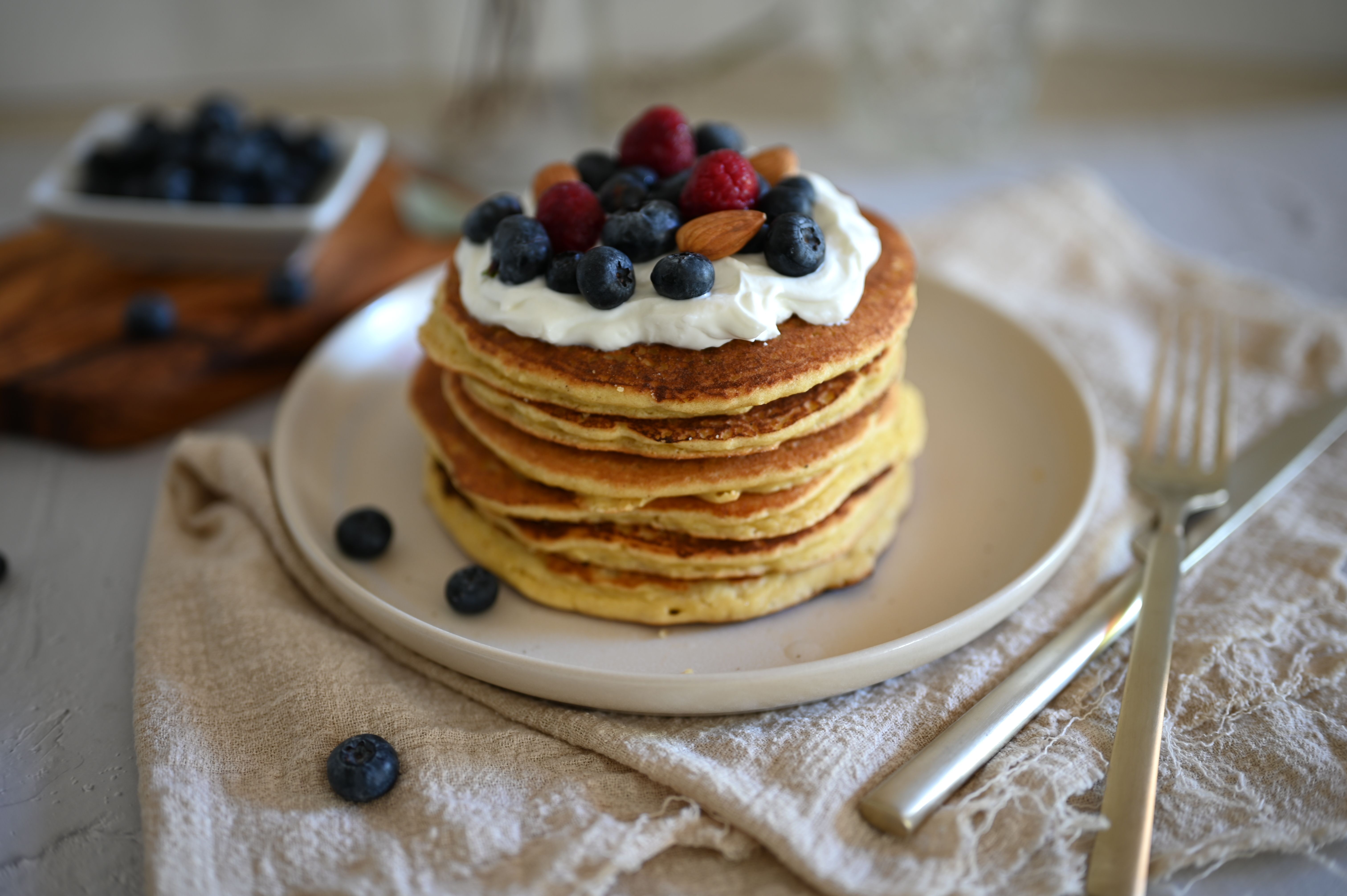 Pile de pancakes cétogènes moelleux, chantilly, myrtilles, framboises et amandes.