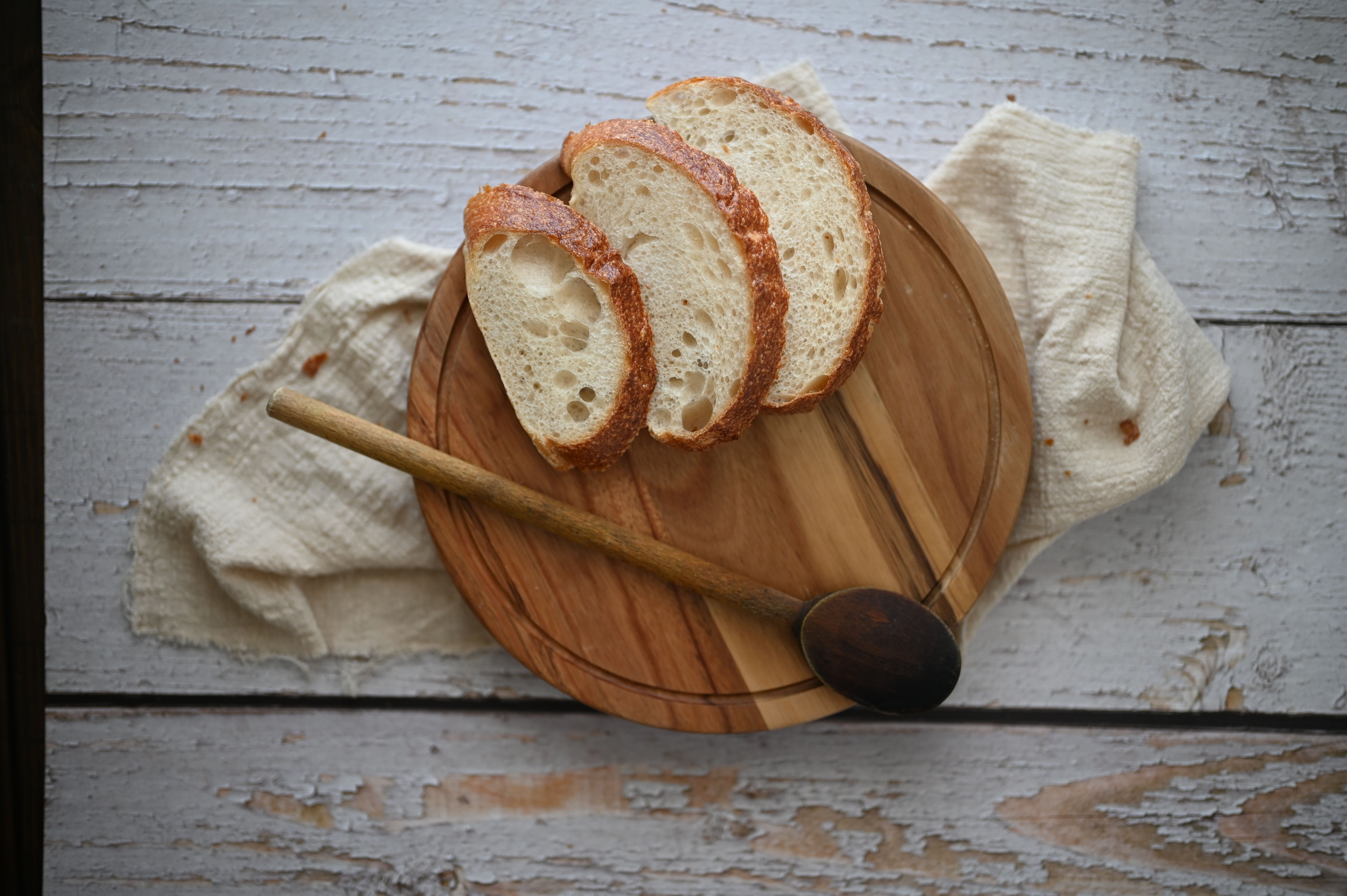 Artistic top-down view of sliced artisan bread on a wooden board with a spoon.