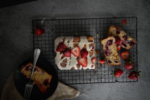 Freshly baked strawberry cake with white icing on a cooling rack, perfect for dessert lovers.