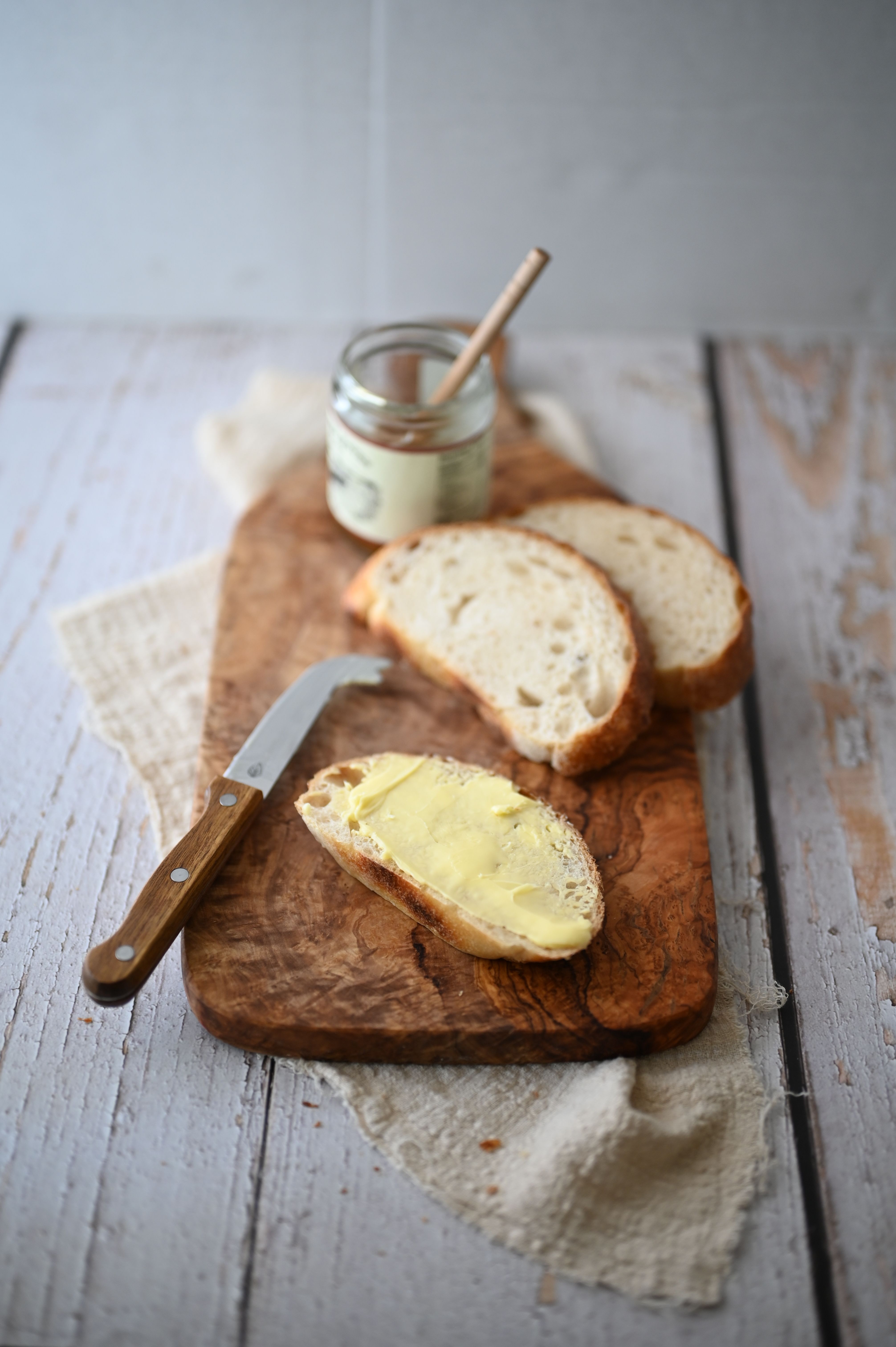 A stick of butter next to a bottle of oil on a wooden cutting board
