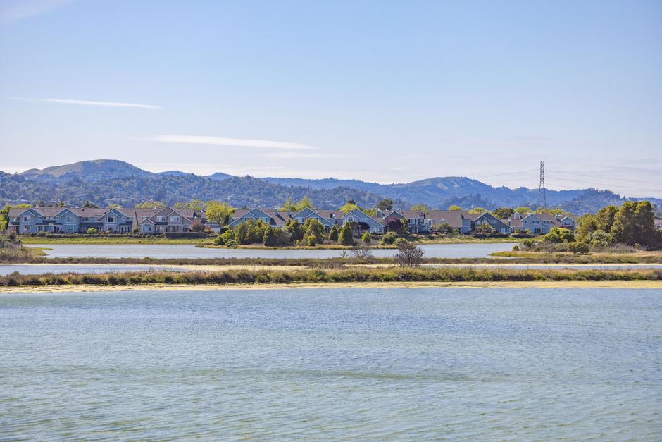 Beautiful view of lakeside houses framed by distant mountains under a clear blue sky.