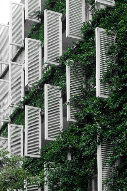 Sleek residential building featuring vertical gardens and open shutters.