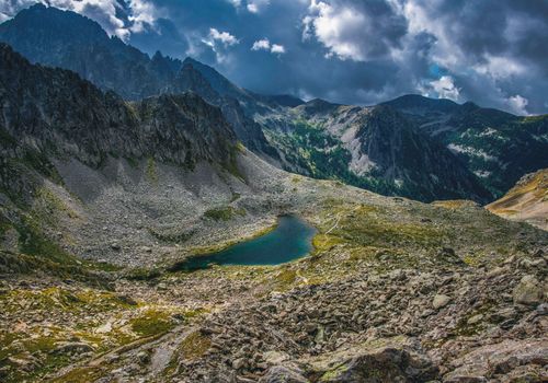 Green and Gray Mountains Beside Lake Under Blue and Cloudy Sky