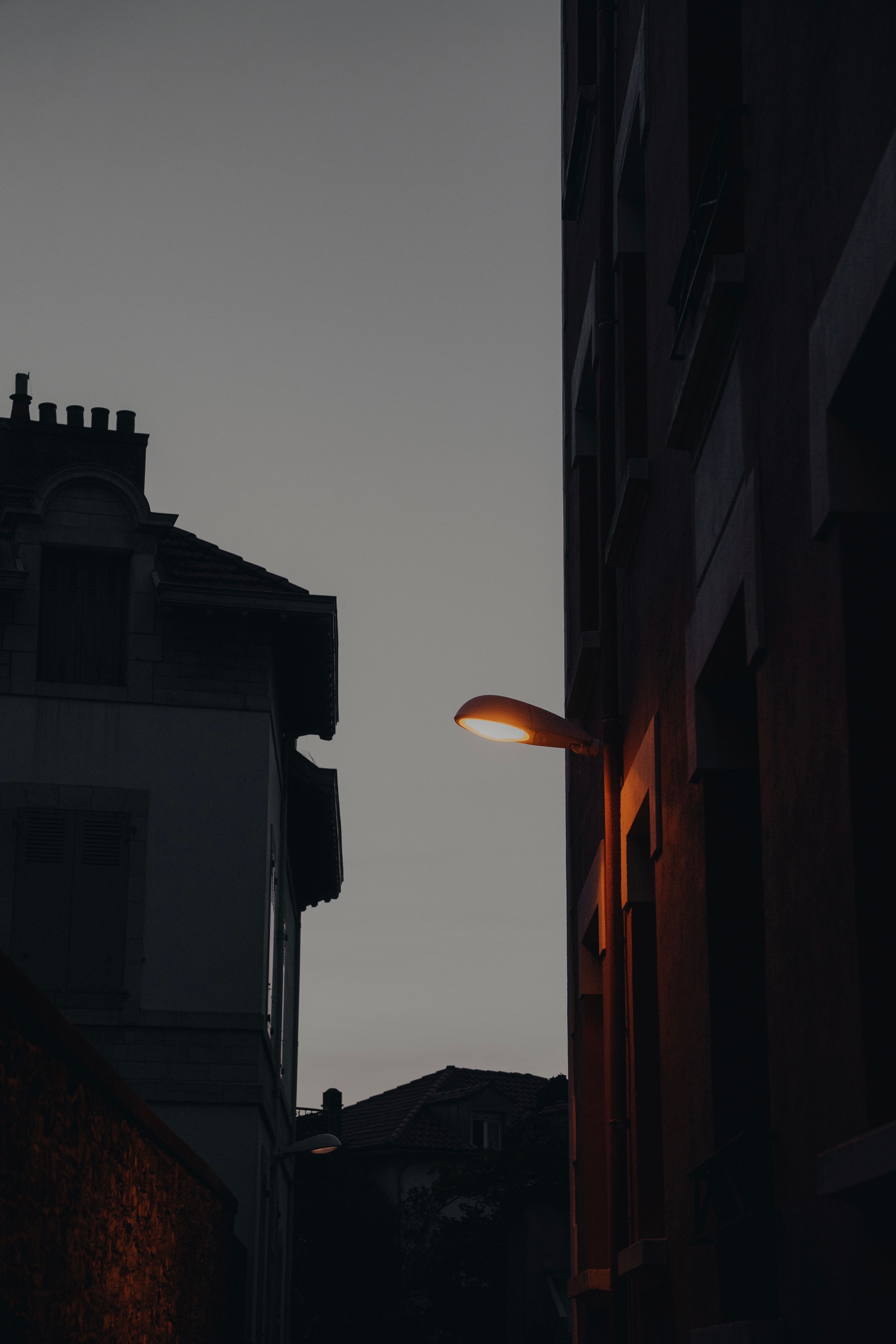 A dimly lit urban street scene captured at dusk, featuring a glowing street lamp.