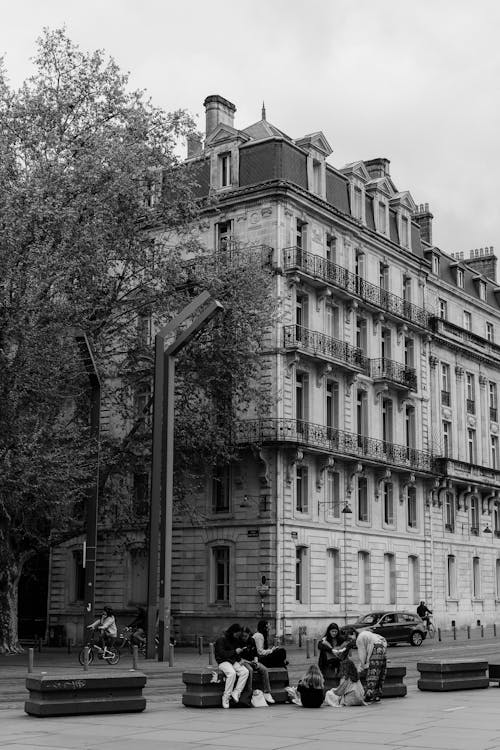 Black and White Photo of People Resting on Plaza in front of Old Townhouse