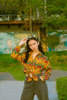 Woman posing outdoors in vibrant, colorful attire with a stylish and confident look.