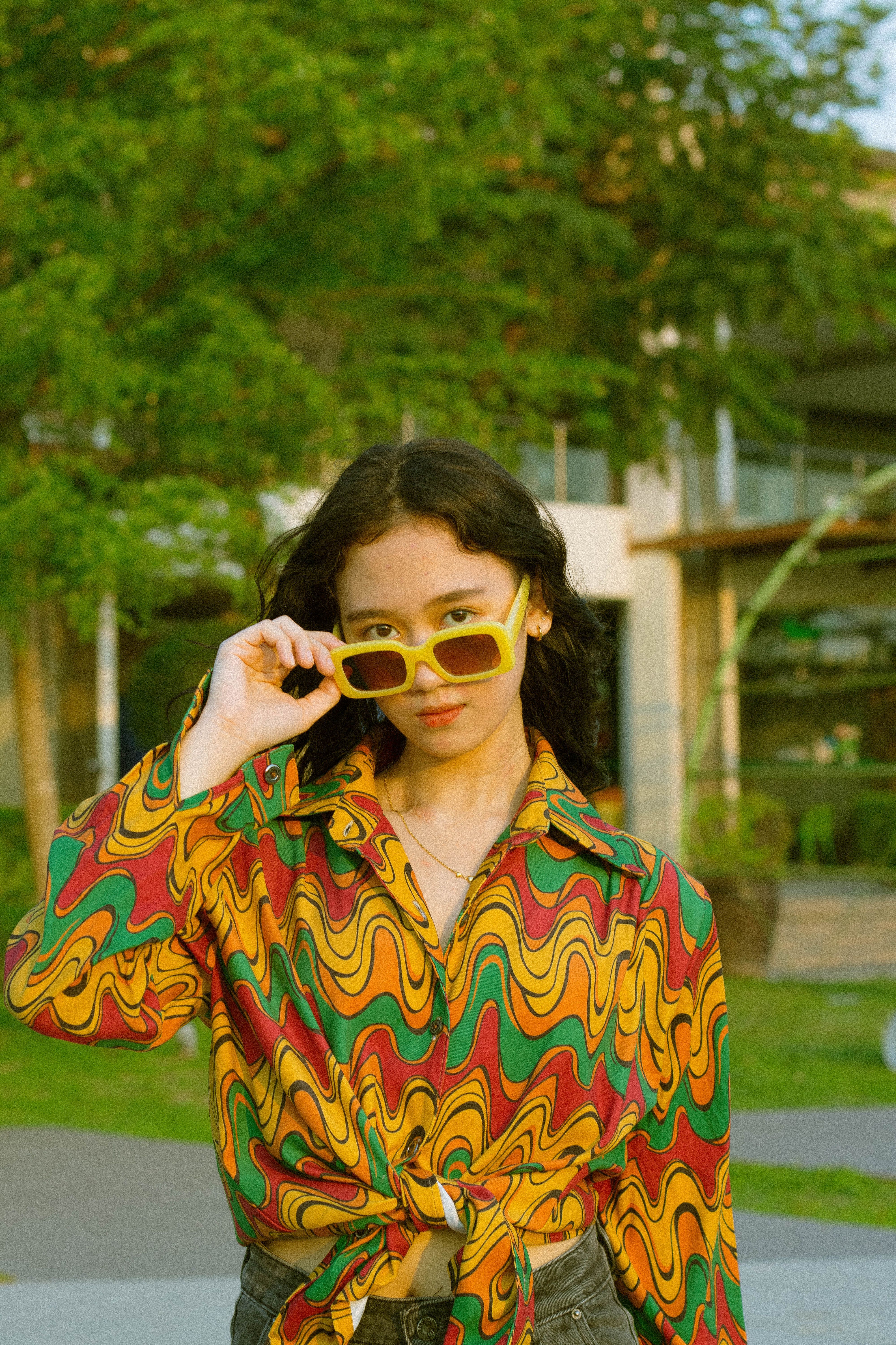 Fotomural Mujer con camisa vibrante y gafas de sol posando al aire libre durante el día.