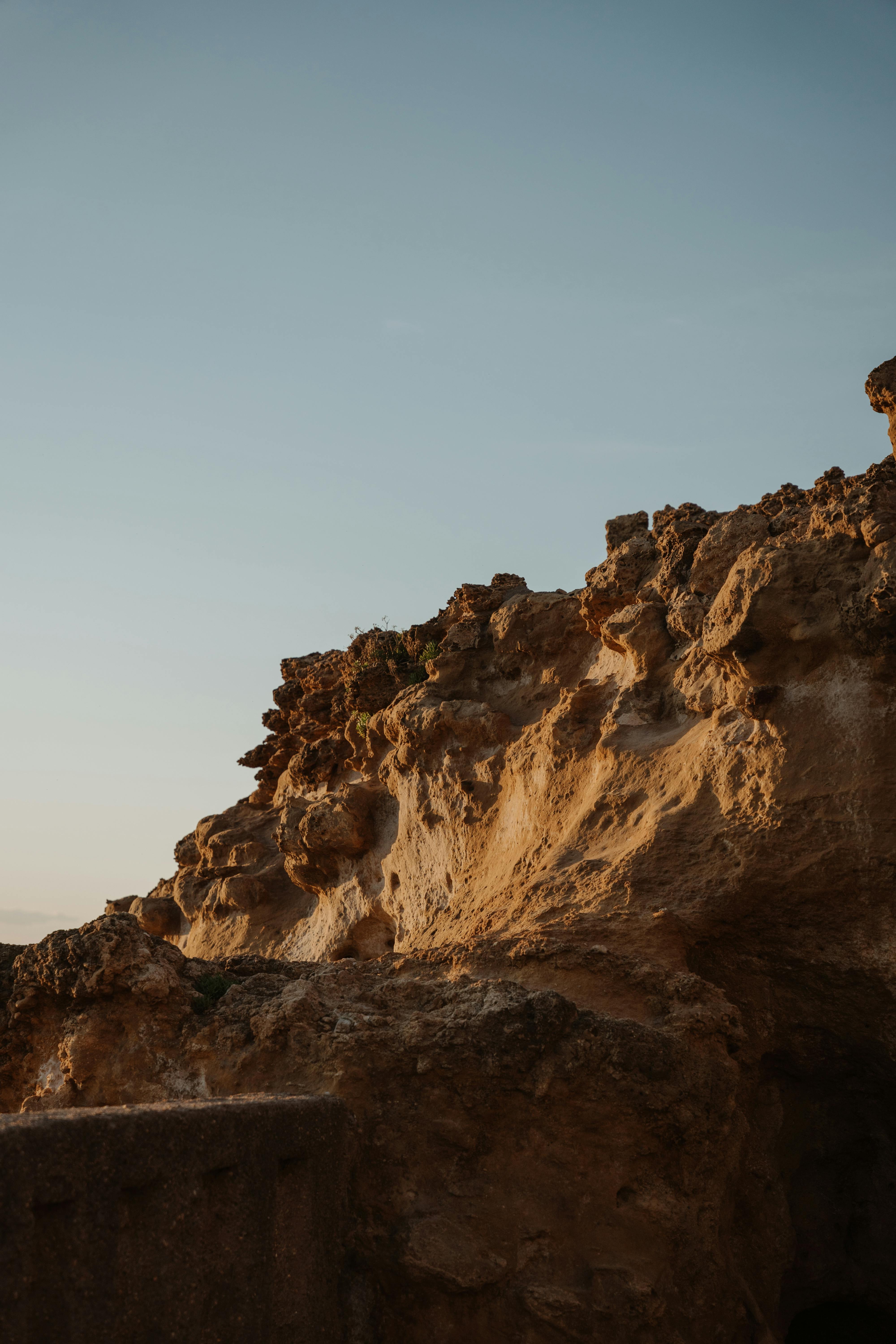 Dramatic rustic rock formations captured under a clear blue sky at sunset.