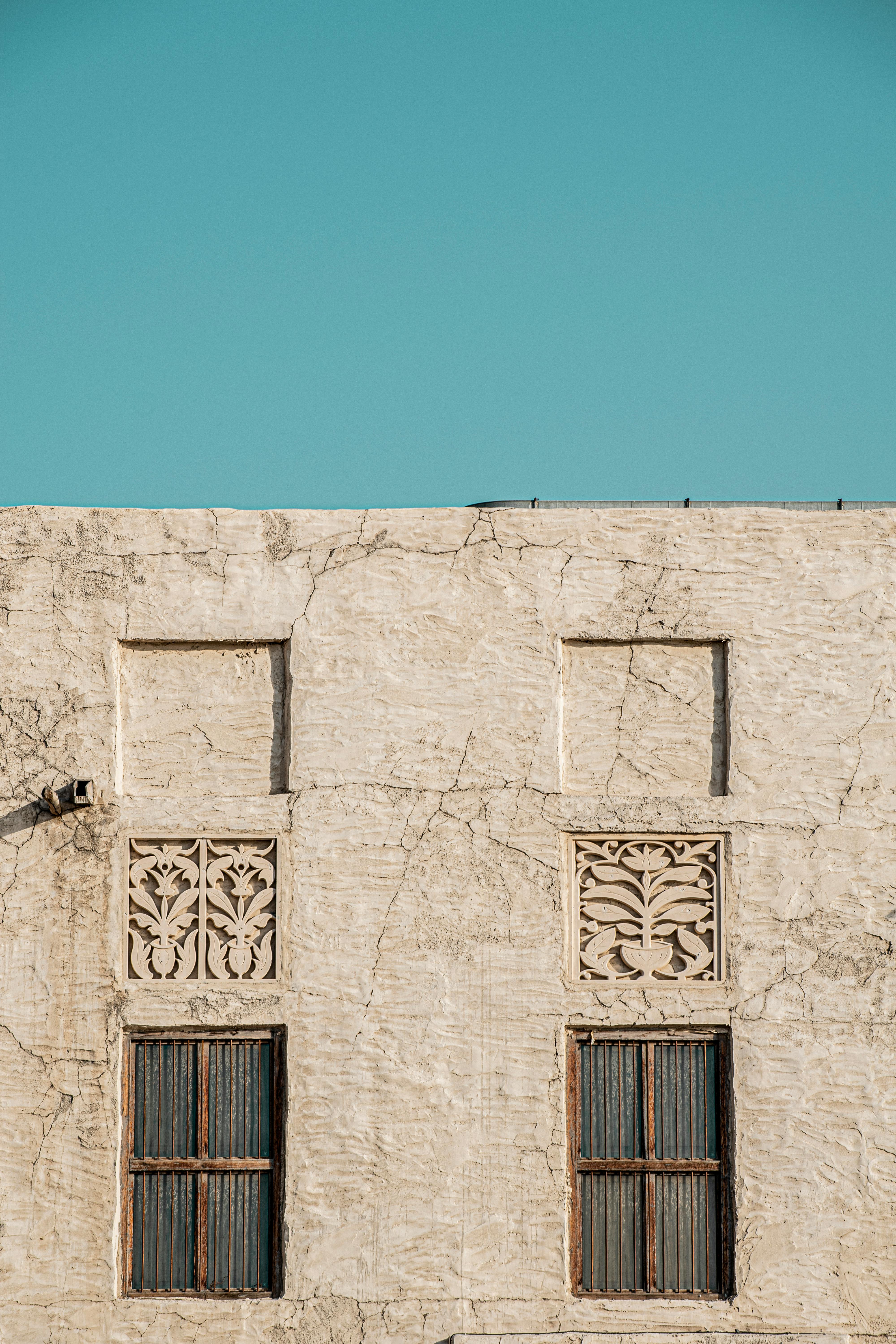 Traditional house facade in Dubai with ornamental windows against a clear blue sky.