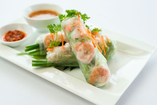 Fresh Vietnamese spring rolls on a plate with dipping sauces, perfect for food photography and culinary inspiration.