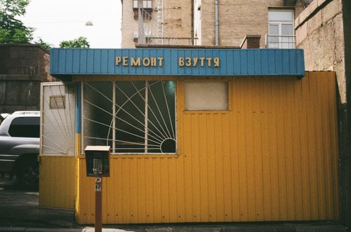 Free A vibrant yellow and blue shoe repair shop in Kyiv's urban setting. Stock Photo