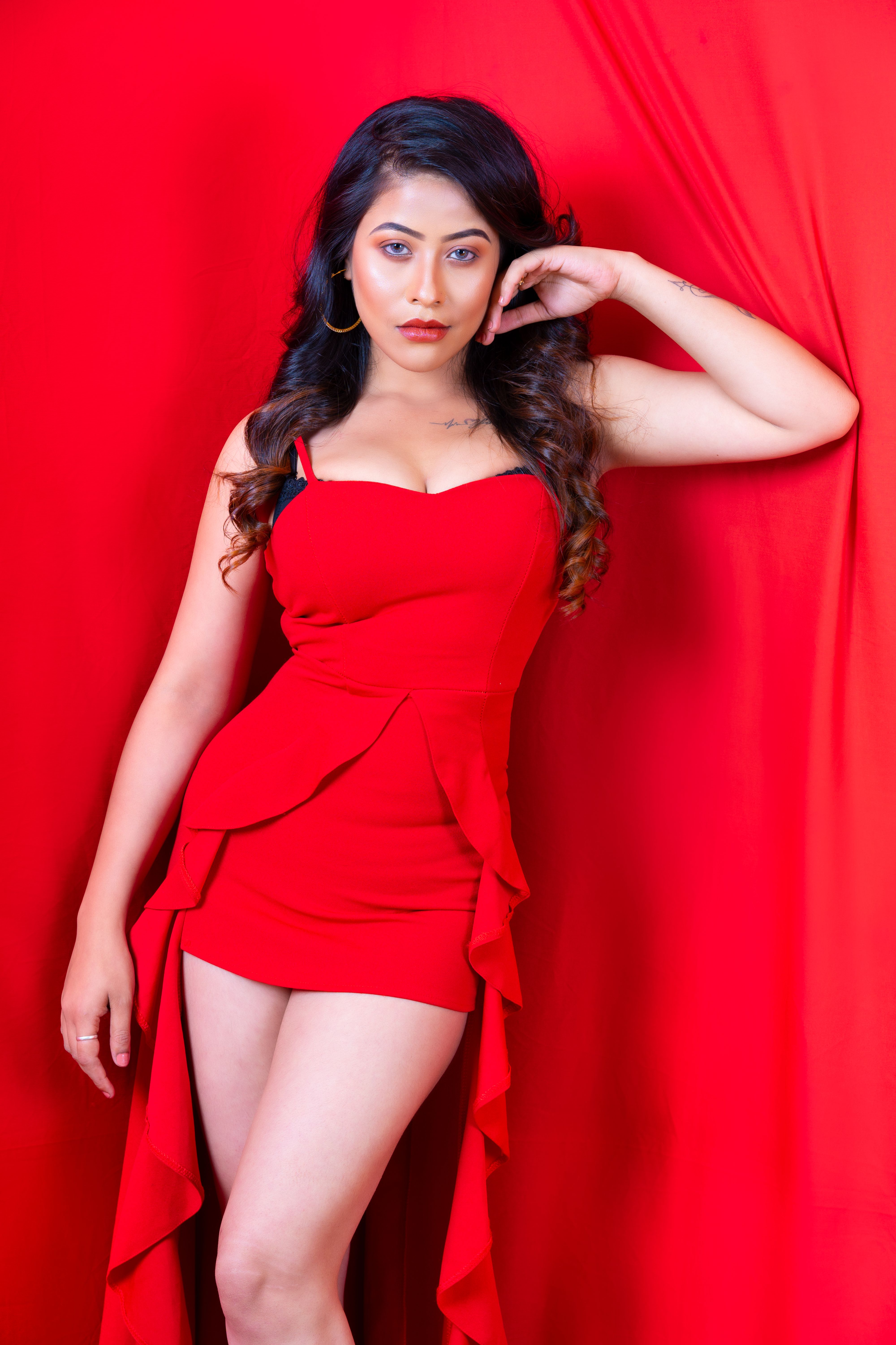 Elegant portrait of a woman posing confidently in a red dress against a red background.