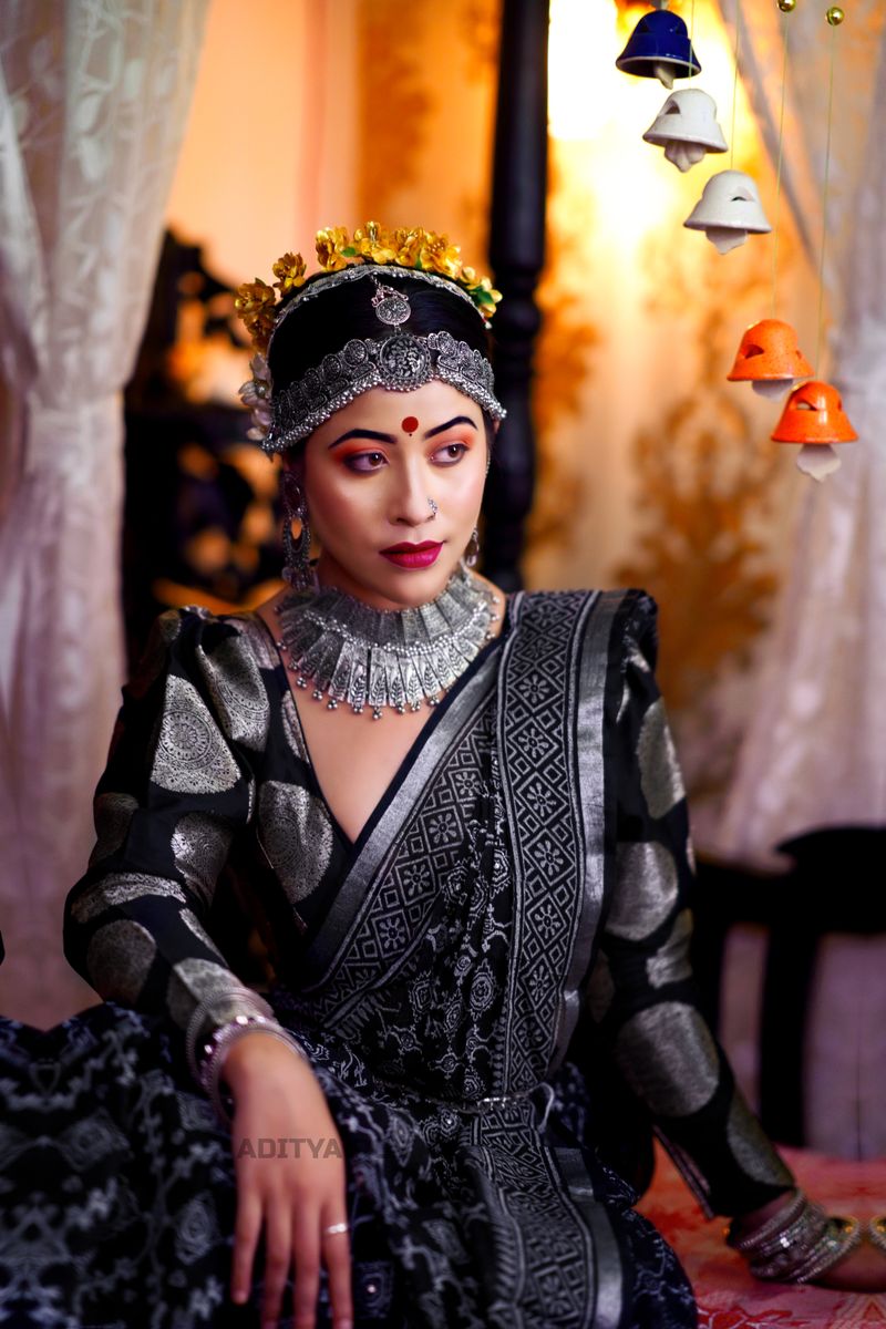 A woman adorned in traditional Indian clothing with intricate jewelry in a warm setting.