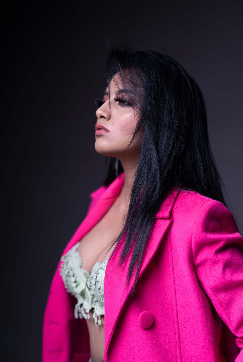 Stylish woman in vibrant pink blazer poses confidently. Elegant and modern look.