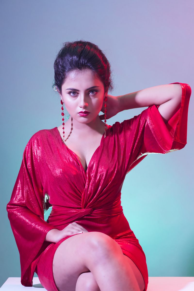 Fashionable young woman in red dress posing in a studio setting.