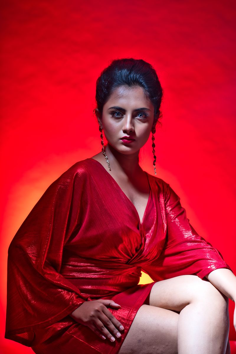 Portrait of a woman in a red dress with striking red background, capturing a dramatic mood.