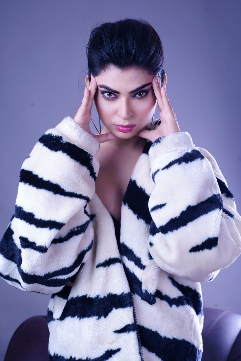 Stylish studio portrait featuring a woman in a fashionable, zebra-print coat.
