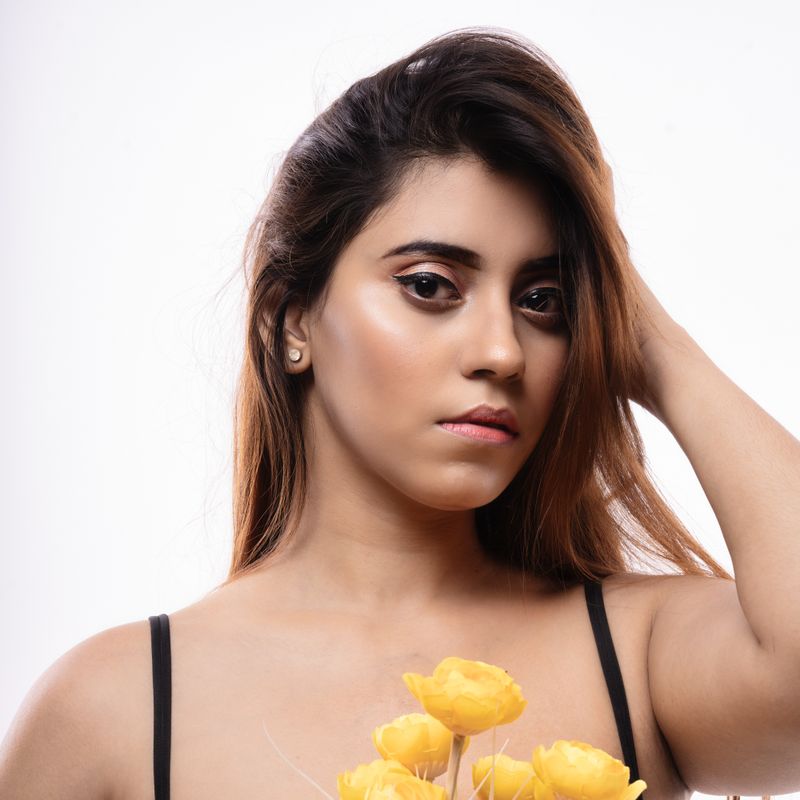 Elegant portrait of a woman with eye makeup holding yellow flowers, exuding a confident and graceful aura.