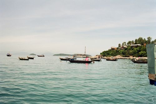 Free Serene view of fishing boats on calm waters near a lush green island. Stock Photo