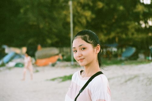 Free A cheerful teenage girl smiling at a sunny beach setting, exuding happiness and leisure. Stock Photo