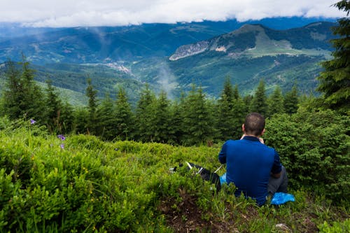 Man Wearing Blue Shirt Sitting On Green Grass 