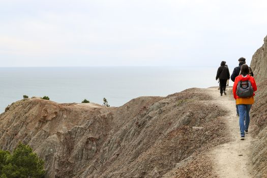 Group of hikers exploring a scenic coastal trail on rocky cliffs in Ukraine. Perfect for adventure and travel concepts.