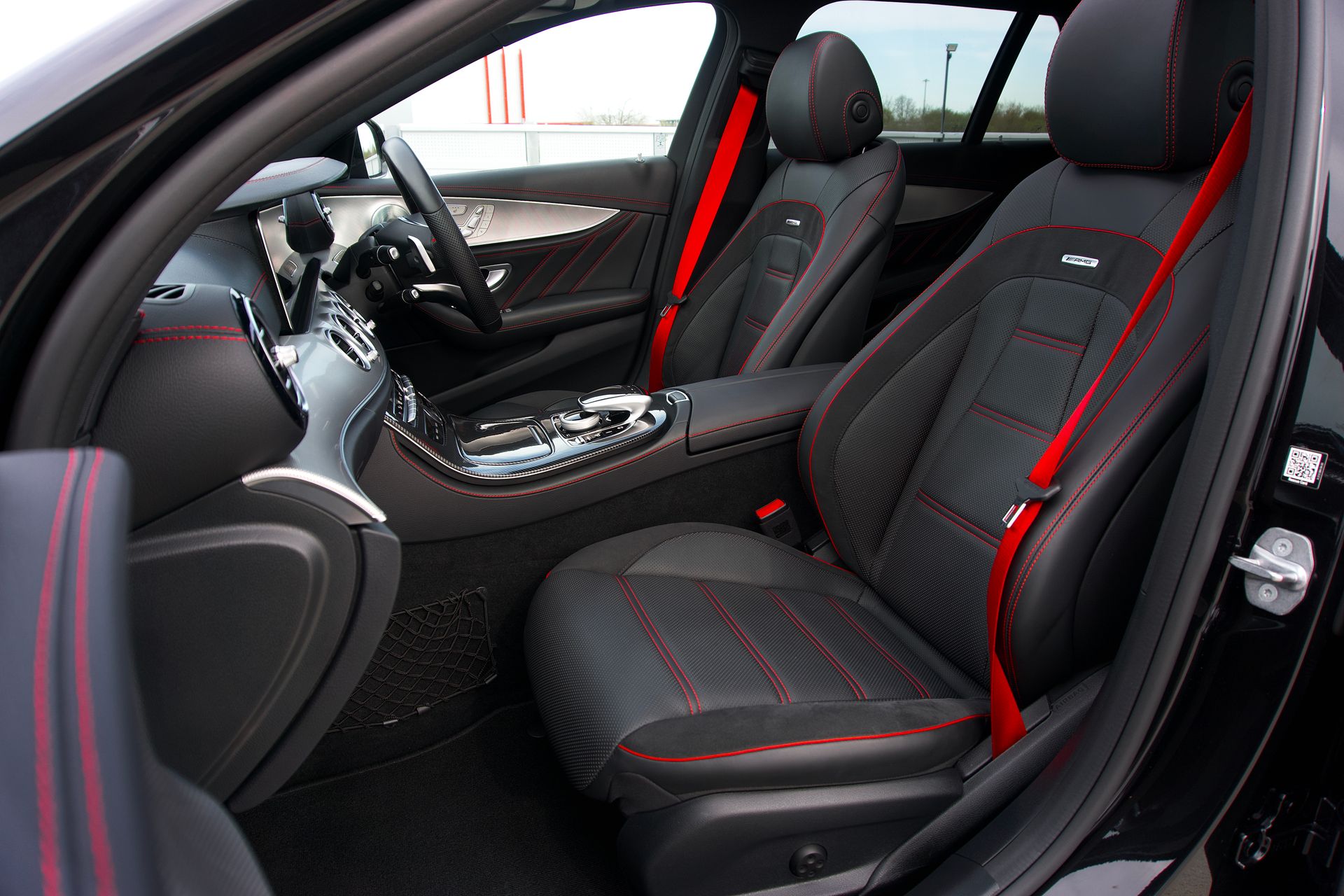 Stylish luxury car interior featuring leather seats, red accents, and modern design elements.