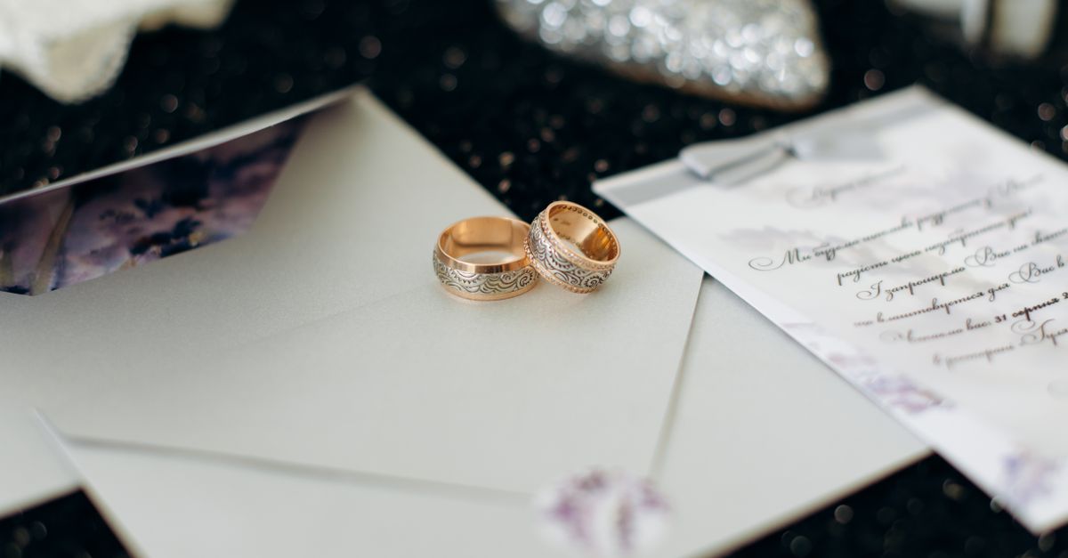 Close-up of elegant wedding rings placed on wedding invitation cards, perfect for marriage themes.
