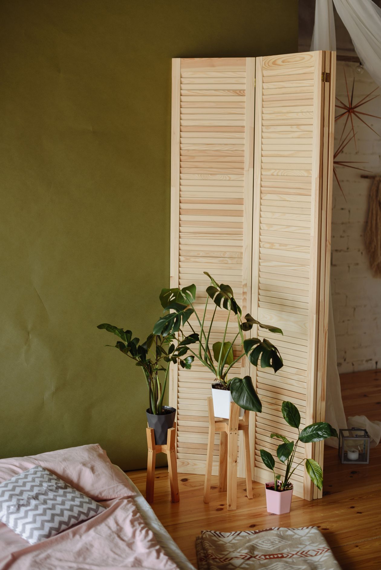 A walnut wooden slatted room divider creating a partial wall between a raised bedroom platform and a small sofa