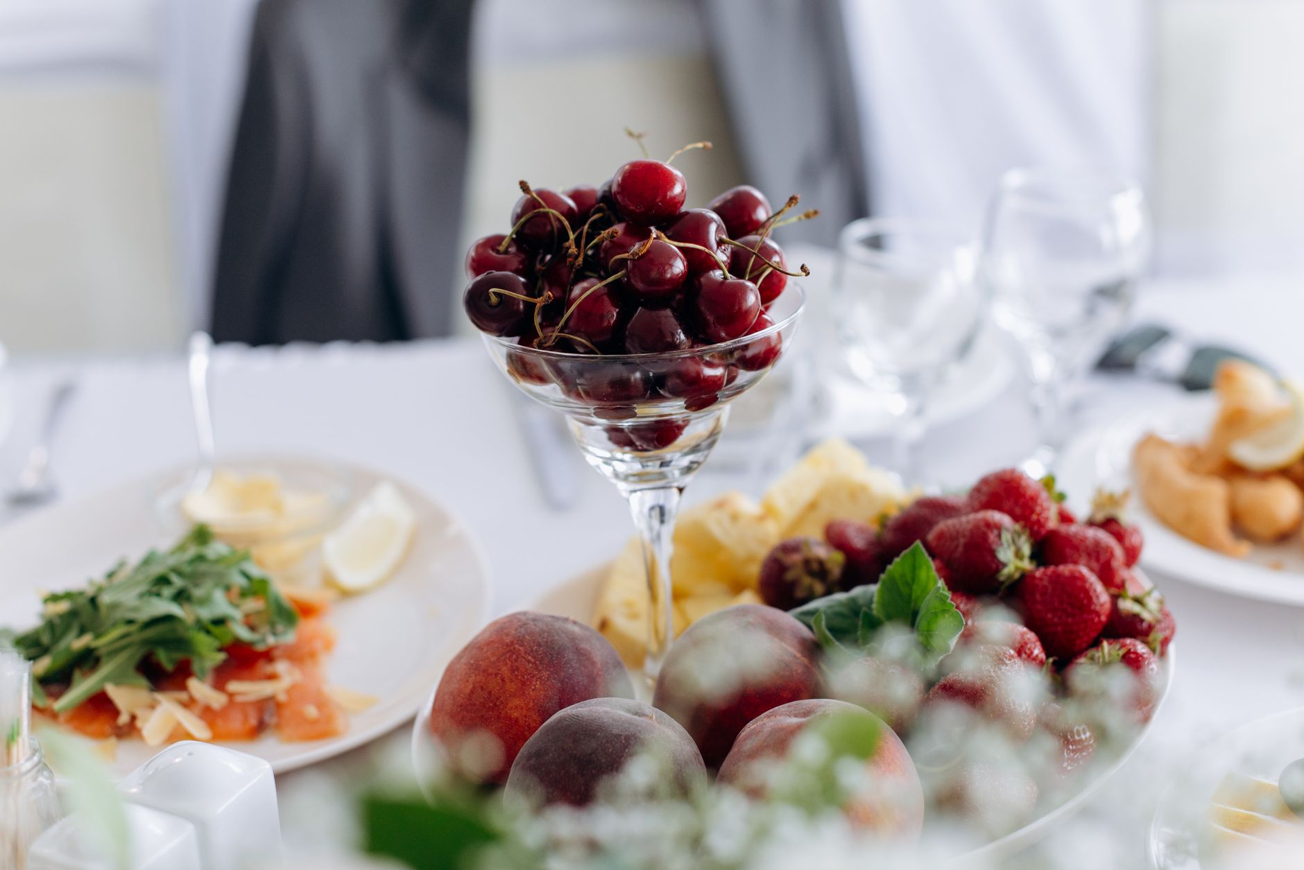 Close-up of cherries, strawberries, and peaches on an elegant table setting.