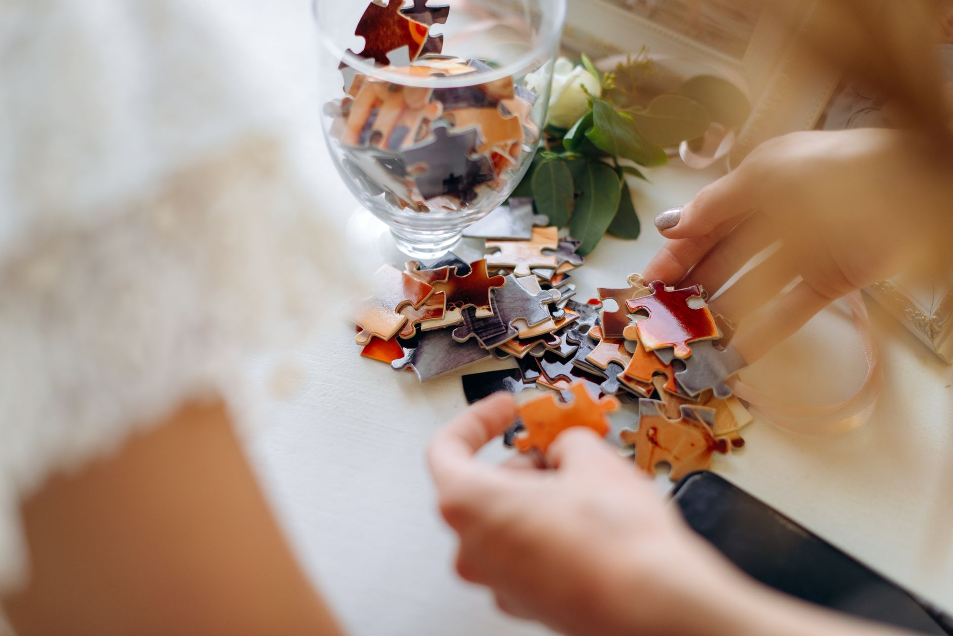 Close-up of a woman assembling colorful puzzle pieces on a table, emphasizing creativity.