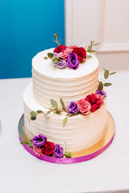 Free A beautifully decorated two-tier white cake with vibrant floral accents ideal for weddings. Stock Photo