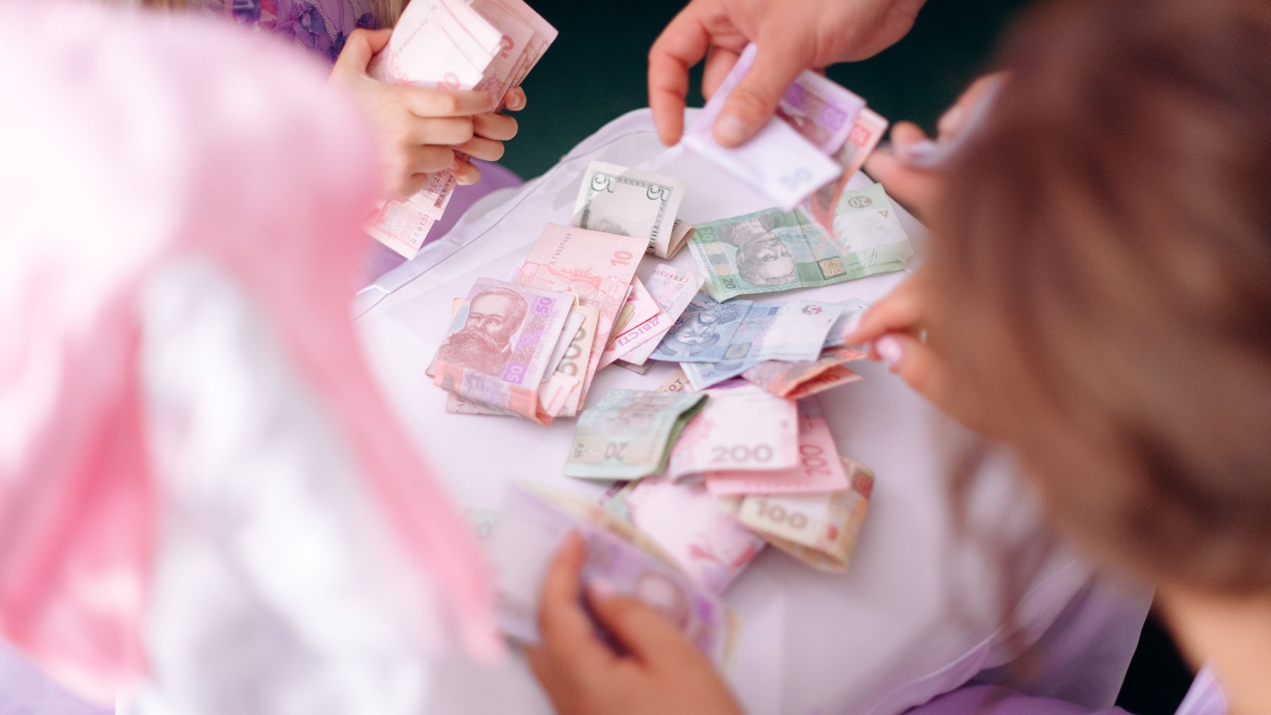 Child and adult hands counting money together as part of a financial learning activity