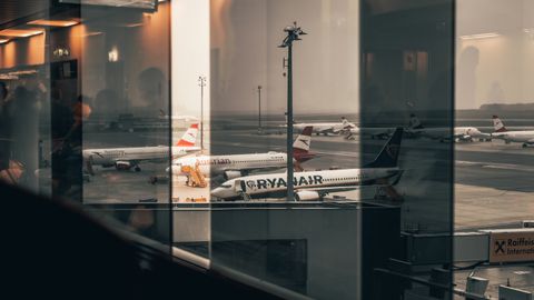 Airplanes at a bustling airport with reflections of interiors in the window panes.