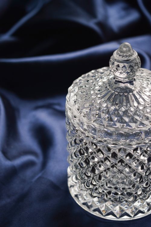 Free Close-up of a decorative crystal jar with lid on rich blue fabric. Stock Photo