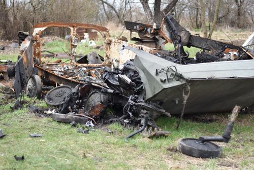 Free A wrecked military vehicle lies in an open field, showing extensive damage and decay. Stock Photo