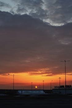 A stunning urban sunrise with silhouetted streetlights and a dramatic cloudy sky, perfect for atmospheric shots.