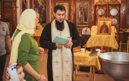 Free A priest conducting a baptism ceremony with family inside an Orthodox church. Stock Photo