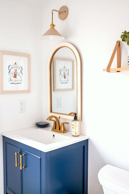 Free Elegant modern bathroom with navy cabinet, gold accents, and wall art. Stock Photo