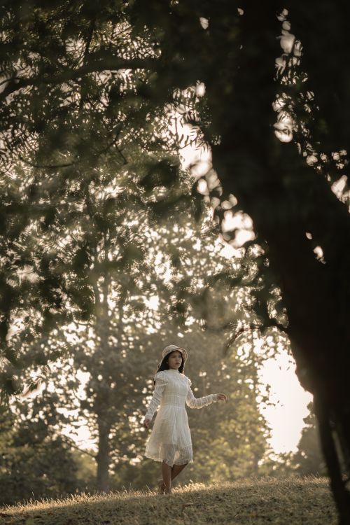 A Young Girl in White Dress Standing Under Green Tree · Free Stock Photo