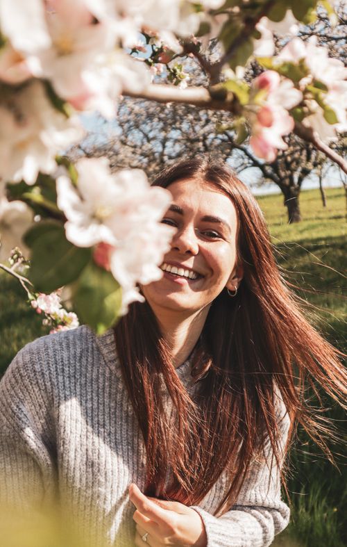 Free A happy woman smiling amidst blooming cherry blossoms on a sunny spring day in Bretten, Germany. Stock Photo