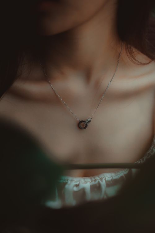 Free Close-up of a woman's necklace in soft, moody lighting showcasing elegance and style. Stock Photo