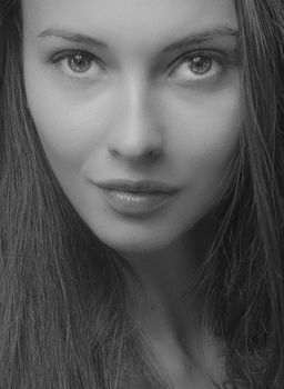 Grayscale close-up headshot of a woman with captivating eyes and serene expression.