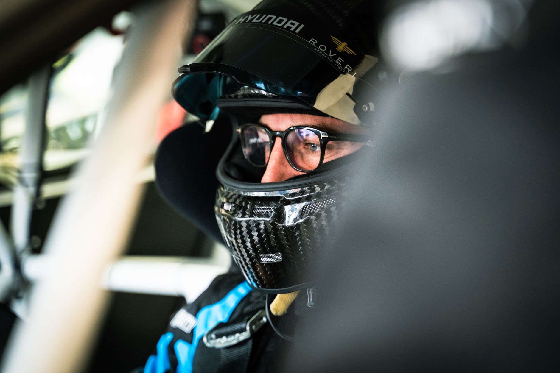 Close-up of a race car driver wearing a helmet in a cockpit at Monza, Italy.