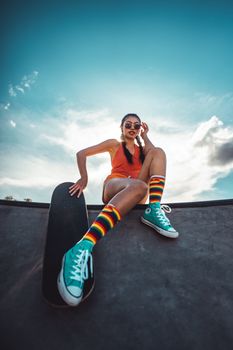 Teen girl in colorful attire enjoys skateboarding at a vibrant skatepark.
