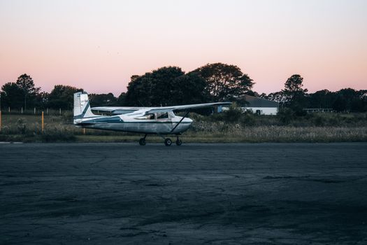 A small aircraft parked on a rural runway during sunset, capturing a serene aviation scene.