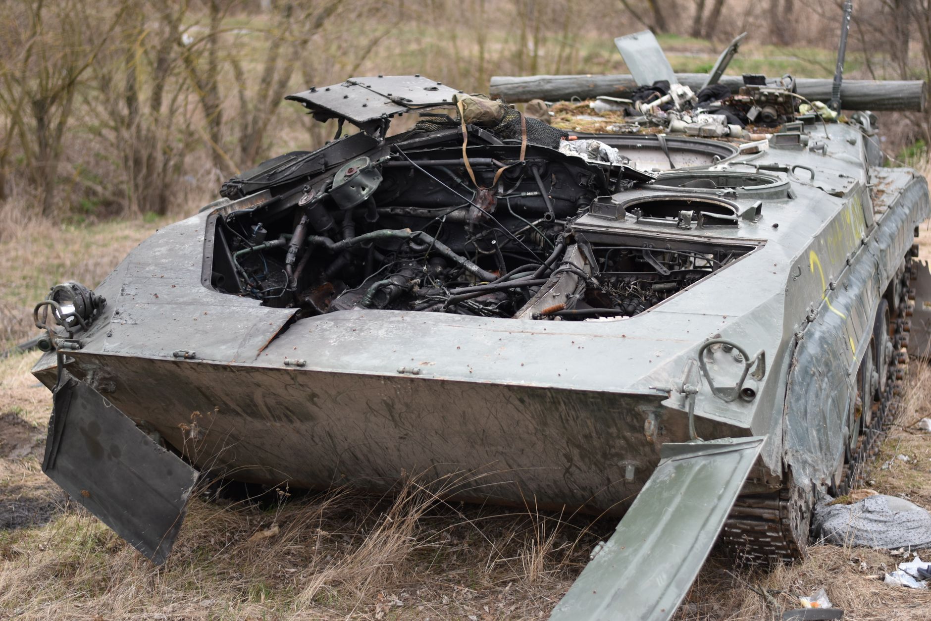 Close-up of a destroyed military tank in an outdoor setting, emphasizing war's impact.
