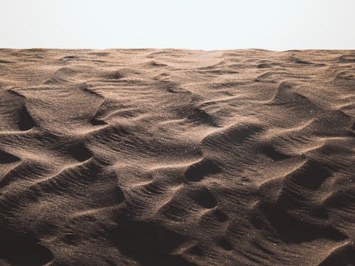 Brown Sand Dunes Under White Sky