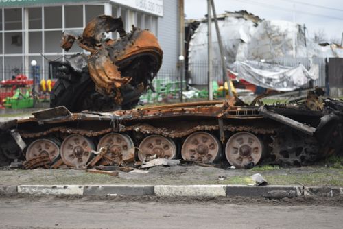 Free A rusted and damaged military tank lies abandoned on a city street. Stock Photo