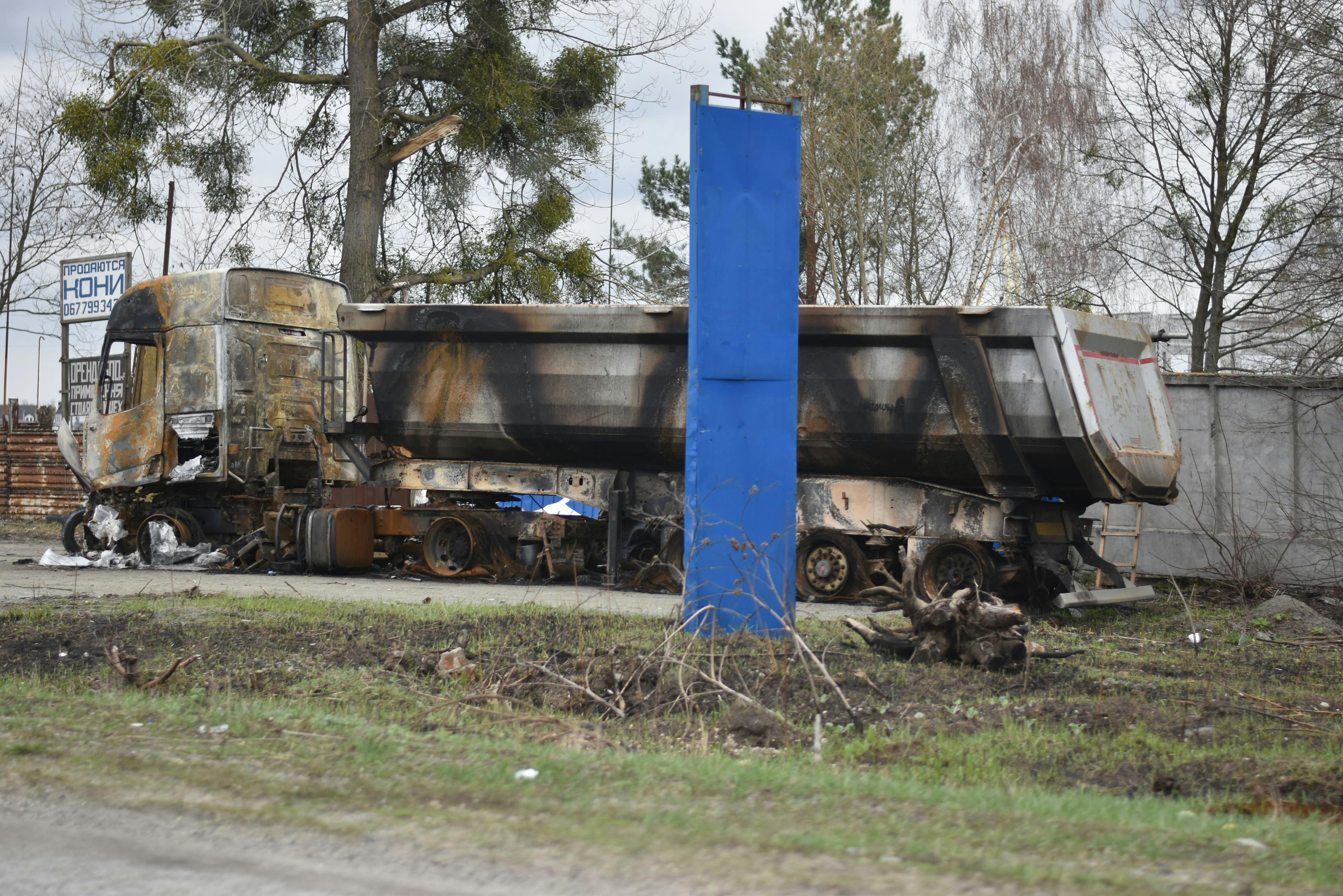 A heavily damaged and burnt truck left abandoned in a city street, creating a scene of destruction.